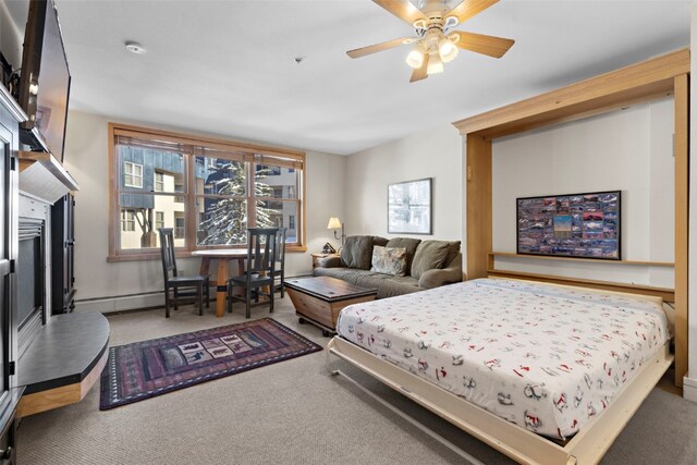 living room featuring baseboard heating, a tiled fireplace, and light carpet