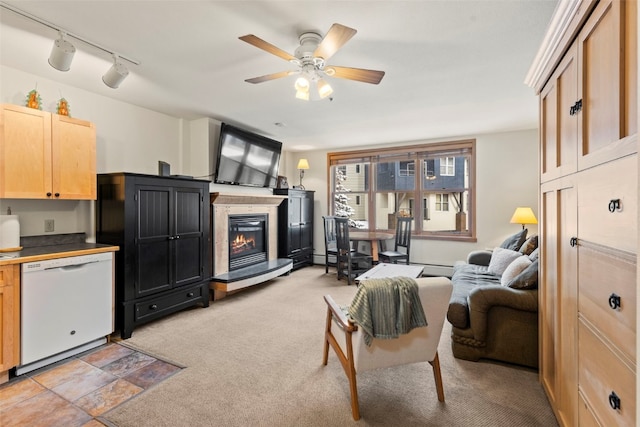 living area with light carpet, rail lighting, a ceiling fan, and a glass covered fireplace