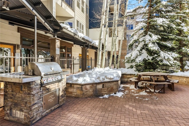 snow covered patio with fence, grilling area, and area for grilling