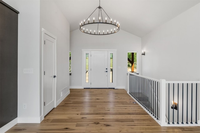 foyer entrance with wood-type flooring, vaulted ceiling, and a notable chandelier