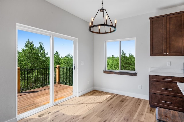 unfurnished dining area featuring a notable chandelier and light wood-type flooring