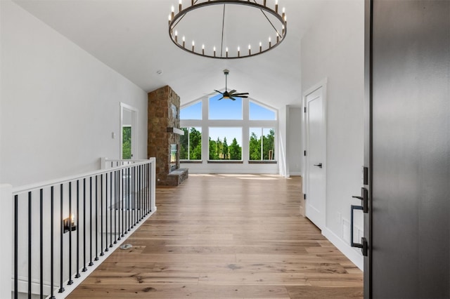 corridor with hardwood / wood-style floors, high vaulted ceiling, and an inviting chandelier