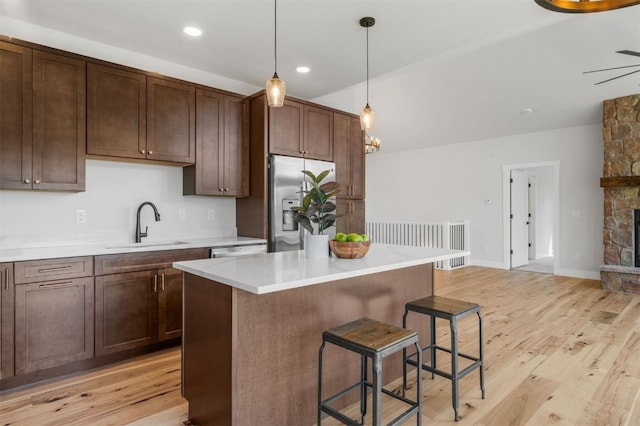 kitchen featuring hanging light fixtures, sink, light hardwood / wood-style flooring, appliances with stainless steel finishes, and a kitchen island