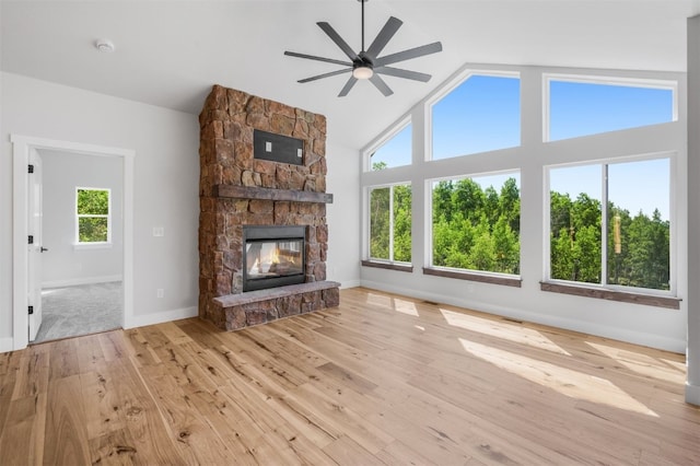 unfurnished living room with ceiling fan, lofted ceiling, a fireplace, and light hardwood / wood-style flooring