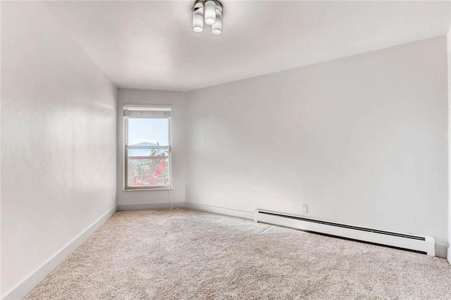 carpeted empty room featuring a baseboard heating unit