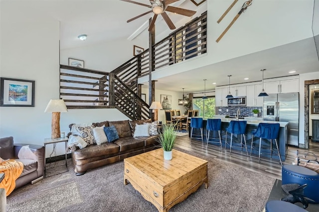 living room with ceiling fan with notable chandelier and high vaulted ceiling