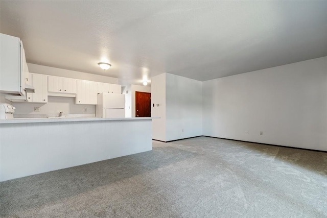 kitchen featuring kitchen peninsula, white cabinetry, white fridge, and light carpet