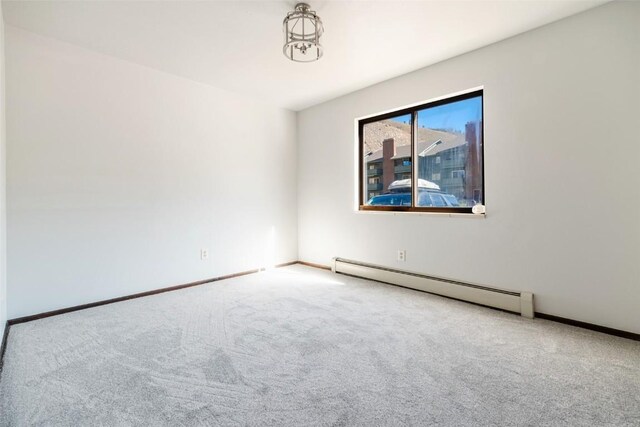 unfurnished room featuring carpet and a baseboard heating unit