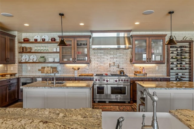 kitchen with range with two ovens, sink, pendant lighting, and light stone counters