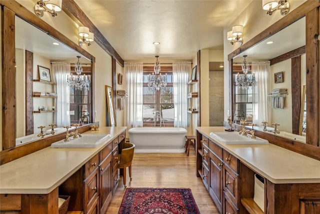 interior space with vanity, a chandelier, hardwood / wood-style floors, and a tub