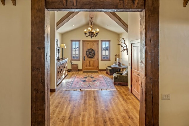 foyer with lofted ceiling with beams, an inviting chandelier, and light hardwood / wood-style flooring