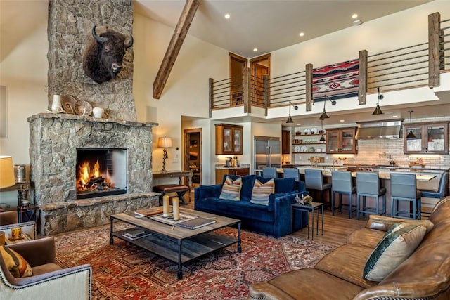 living room with a stone fireplace, a high ceiling, and hardwood / wood-style flooring