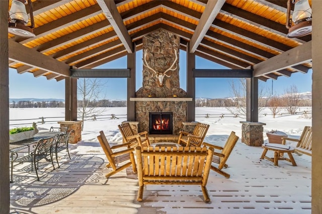 snow covered patio featuring a gazebo and an outdoor stone fireplace