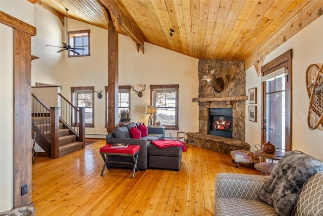 living room with wood ceiling, ceiling fan, baseboard heating, a fireplace, and light wood-type flooring