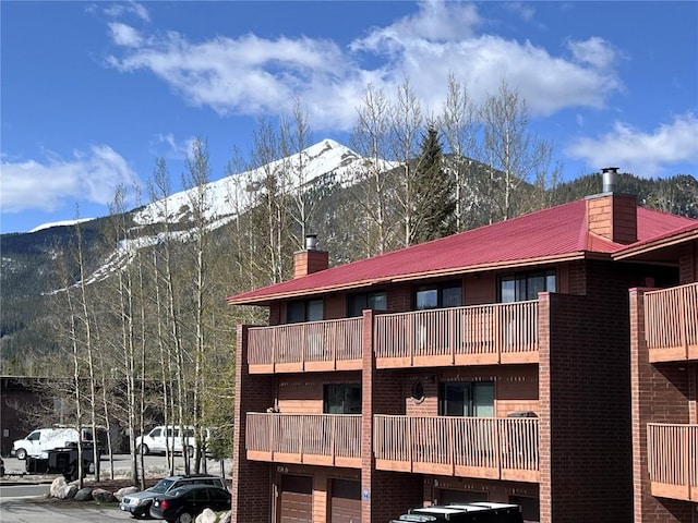 rear view of house featuring a chimney, a mountain view, metal roof, and brick siding