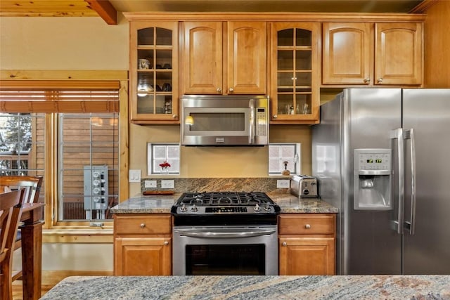 kitchen with light stone countertops, appliances with stainless steel finishes, and beamed ceiling