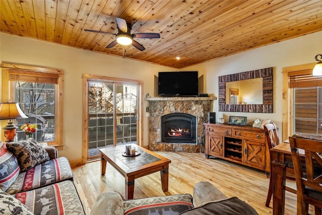 living room with a stone fireplace, wooden ceiling, a ceiling fan, and wood finished floors