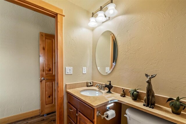 bathroom with wood-type flooring, vanity, and toilet