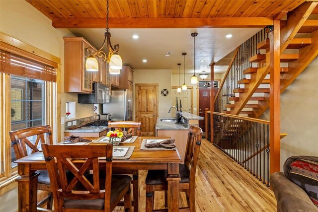 dining area featuring a stone fireplace, wood ceiling, ceiling fan with notable chandelier, and light wood-type flooring