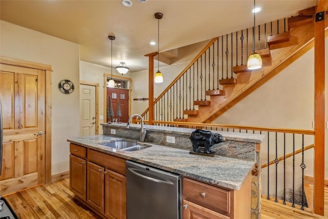 kitchen featuring stainless steel dishwasher, decorative light fixtures, sink, and a center island with sink