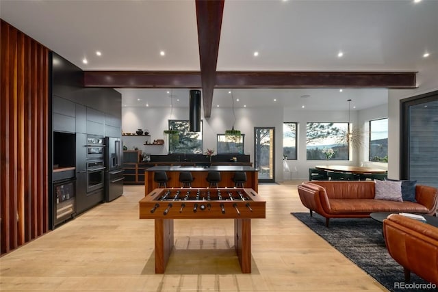 game room featuring beam ceiling and light hardwood / wood-style flooring