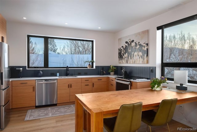 kitchen featuring light brown cabinetry, sink, light hardwood / wood-style flooring, and stainless steel appliances