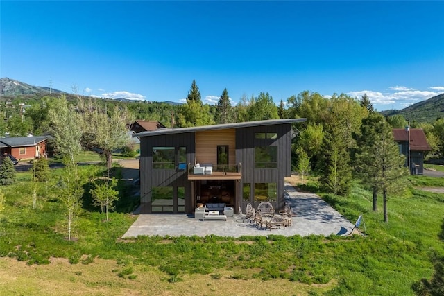 rear view of house featuring a patio area, a mountain view, and a lawn