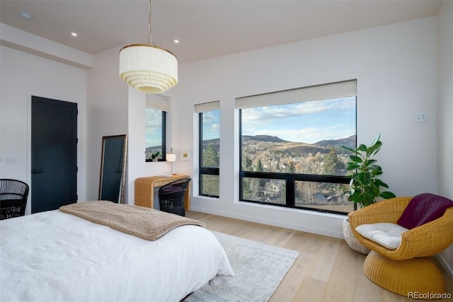 bedroom with a mountain view and light hardwood / wood-style floors