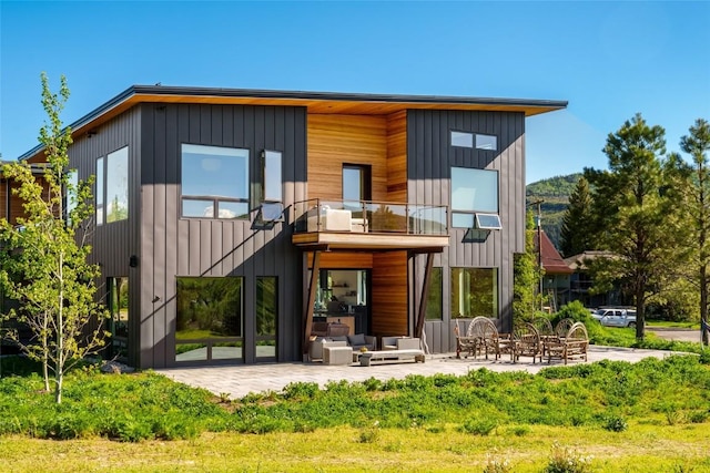 back of property with a balcony, a patio area, and outdoor lounge area