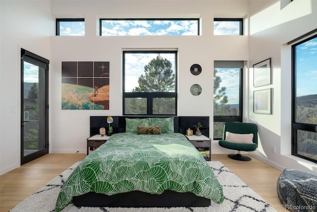 bedroom featuring wood-type flooring and a towering ceiling