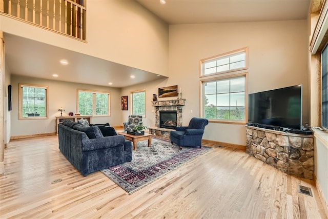 living room featuring a fireplace, high vaulted ceiling, and light hardwood / wood-style flooring