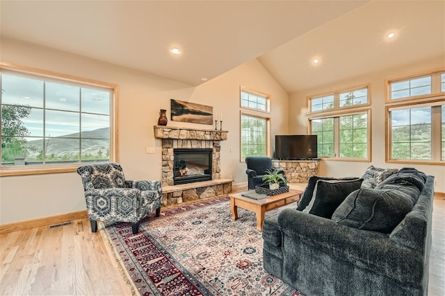 living room featuring hardwood / wood-style flooring, a stone fireplace, and vaulted ceiling