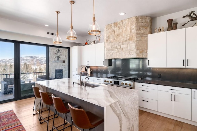 kitchen featuring high end stainless steel range oven, white cabinetry, a mountain view, and sink