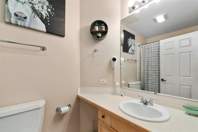 bathroom featuring toilet, a shower with shower curtain, and vanity