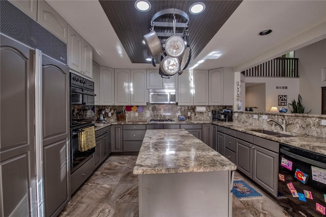 kitchen featuring a kitchen island, light stone countertops, gray cabinets, and black appliances