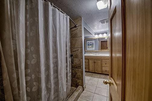 bathroom featuring a shower with curtain, a textured ceiling, and tile patterned floors