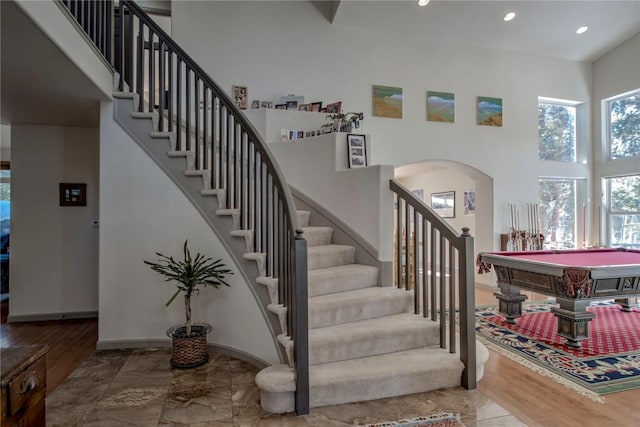 stairway with pool table and a high ceiling