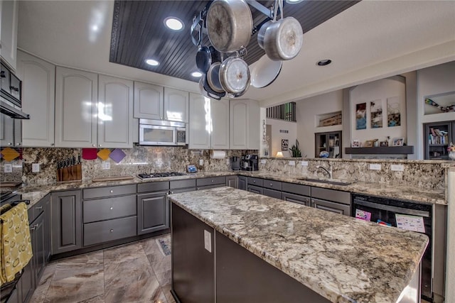 kitchen featuring kitchen peninsula, decorative backsplash, gray cabinets, appliances with stainless steel finishes, and sink