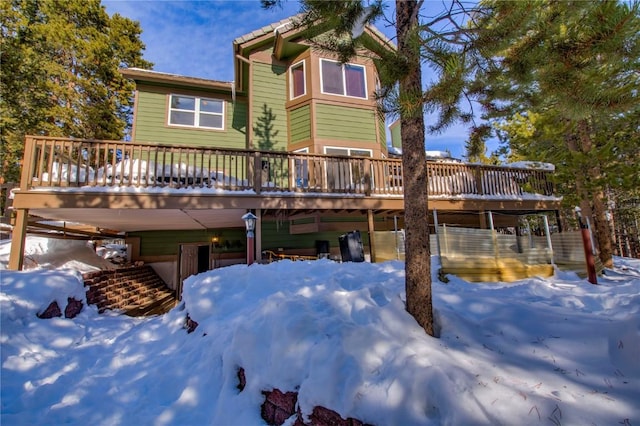 snow covered rear of property with a deck