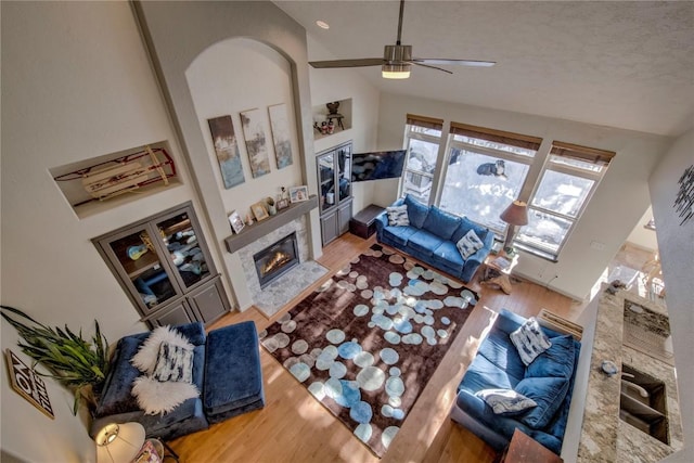 living room with wood-type flooring, high vaulted ceiling, a fireplace, and ceiling fan