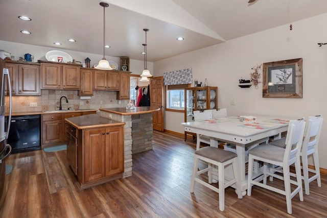 kitchen featuring sink, pendant lighting, dishwasher, a kitchen island, and lofted ceiling