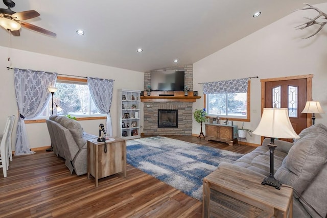 living room featuring dark hardwood / wood-style floors, a stone fireplace, and vaulted ceiling