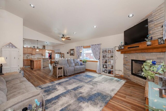 living room featuring lofted ceiling, sink, ceiling fan, a fireplace, and wood-type flooring