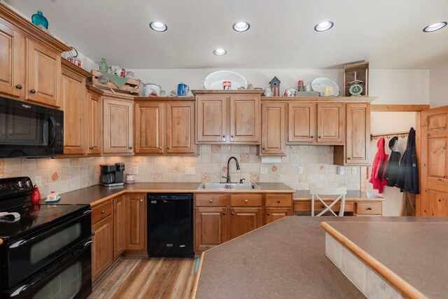 kitchen with sink, tasteful backsplash, light hardwood / wood-style flooring, and black appliances