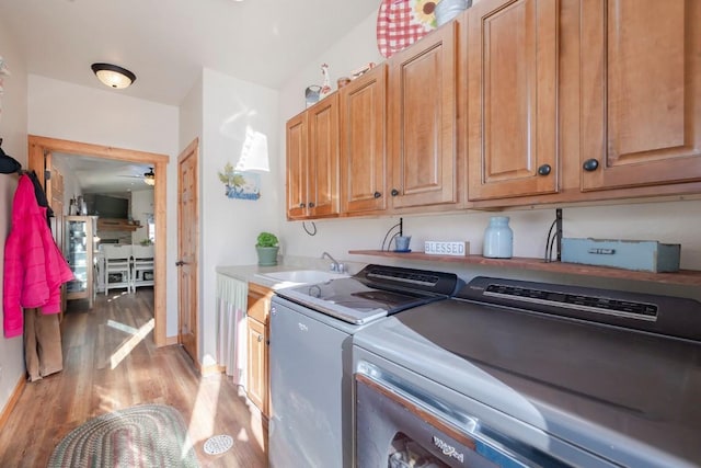 laundry room with ceiling fan, sink, cabinets, washing machine and dryer, and light wood-type flooring