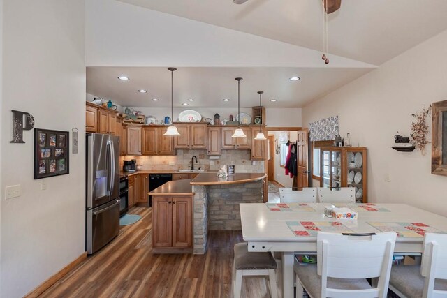 dining room featuring dark wood-type flooring, sink, and vaulted ceiling