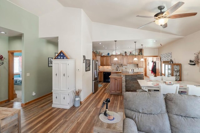 living room featuring hardwood / wood-style floors, vaulted ceiling, ceiling fan, and sink