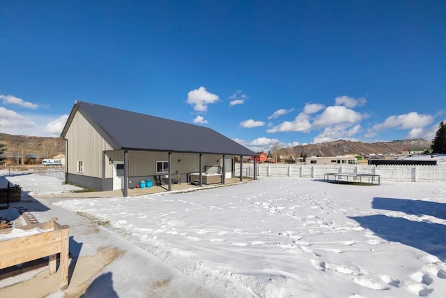 snow covered back of property featuring a mountain view