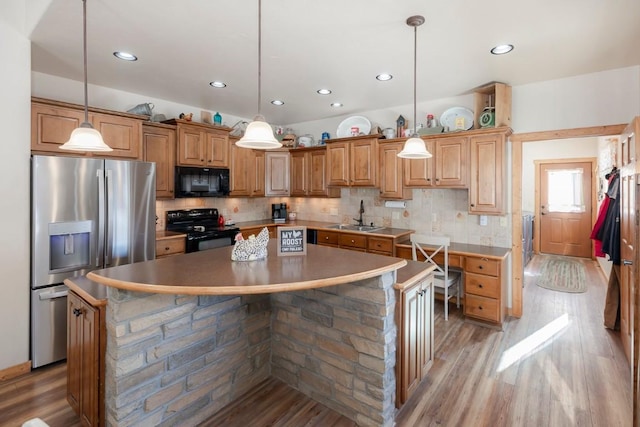 kitchen featuring black appliances, decorative light fixtures, and a kitchen island