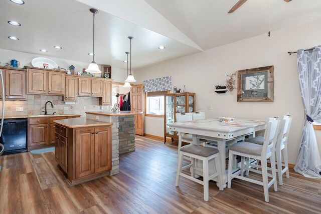 kitchen featuring sink, pendant lighting, black dishwasher, a kitchen island, and lofted ceiling